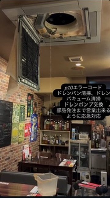 飲食店の天井カセット型エアコンのパネルを開けて点検している様子